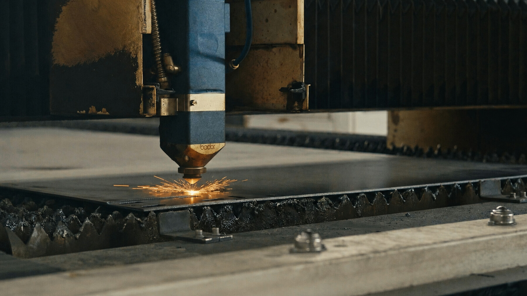 Automated industrial laser cutting a sheet of steel with visible sparks